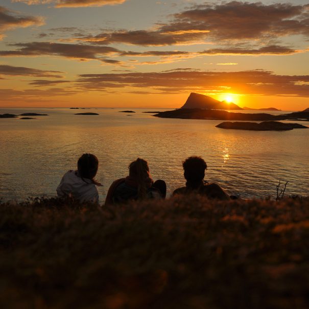 midnight sun group of people watching sunset over ocean and island