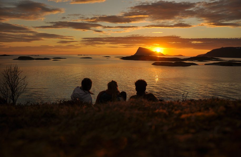 midnight sun group of people watching sunset over ocean and island